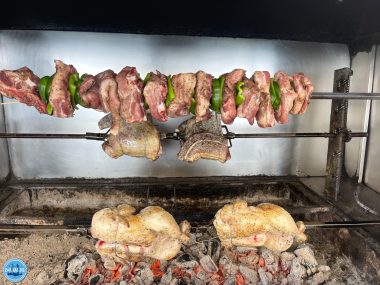 Traditionelles griechisches BBQ auf Kreta bei Zorbas Island mit Fleischspießen und Hähnchen, die langsam über offener Holzkohle gegrillt werden.