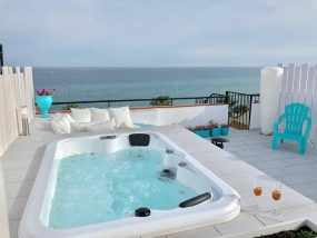 Moderner Outdoor-Whirlpool auf einer weißen Terrasse mit direktem Meerblick und Loungemöbeln in Kokkini Hani auf Kreta.